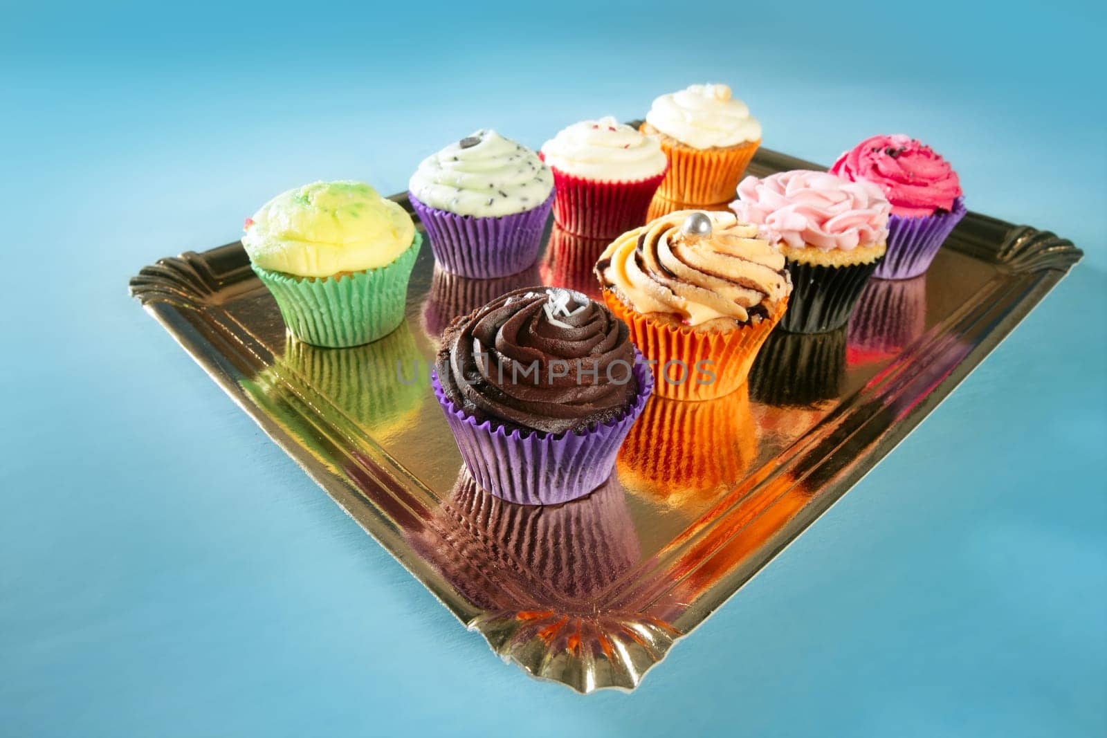 Cupcakes colorful cream muffin arrangement in golden mirror tray