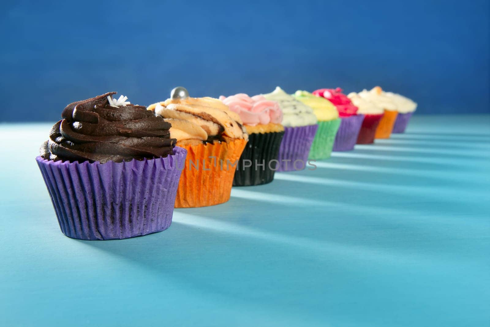 Cupcakes colorful cream muffin arrangement in a row line on turquoise