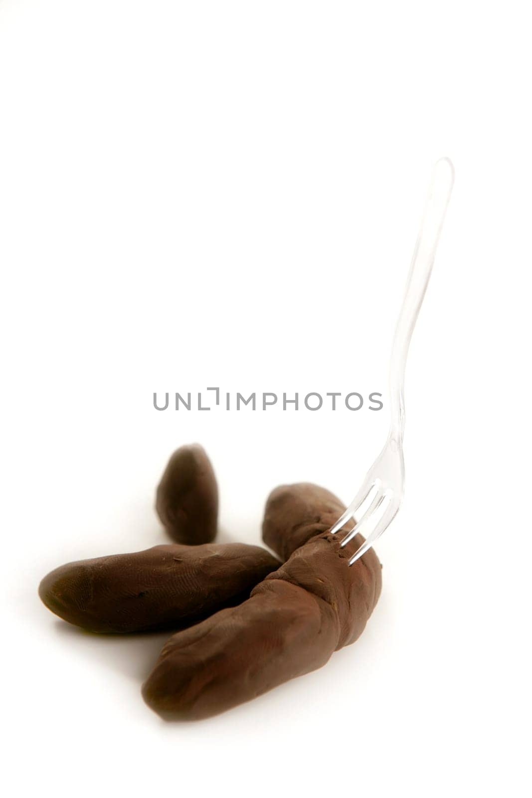 humor image, plascticine excrement with fork, unpleasant handmade menu over white