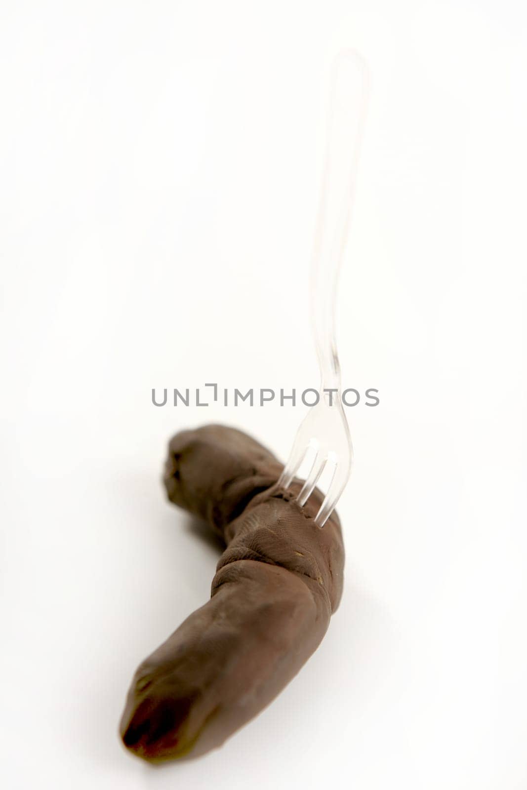 humor image, plascticine excrement with fork, unpleasant handmade menu over white