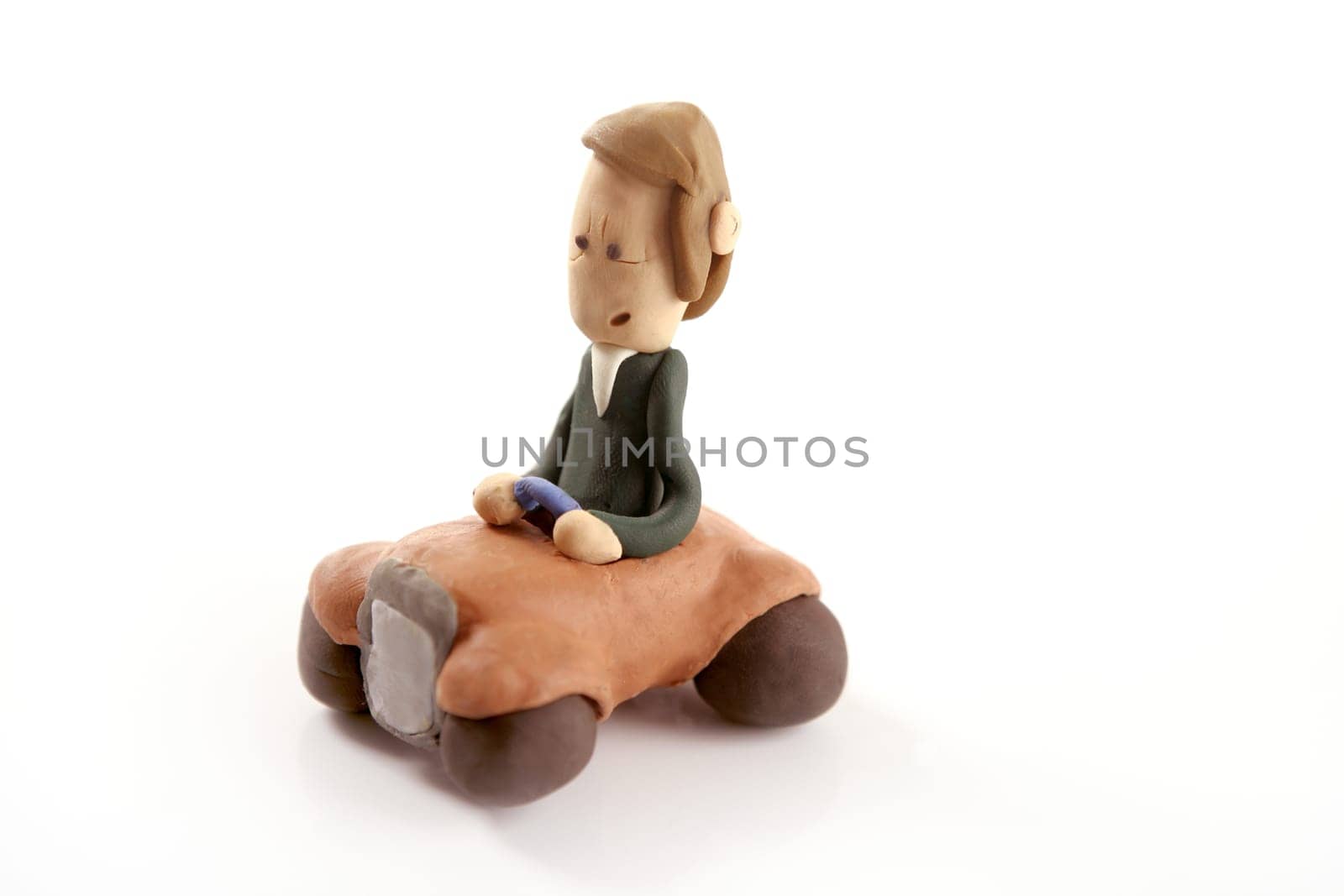 Handmade plasticine man driving a car isolated on white