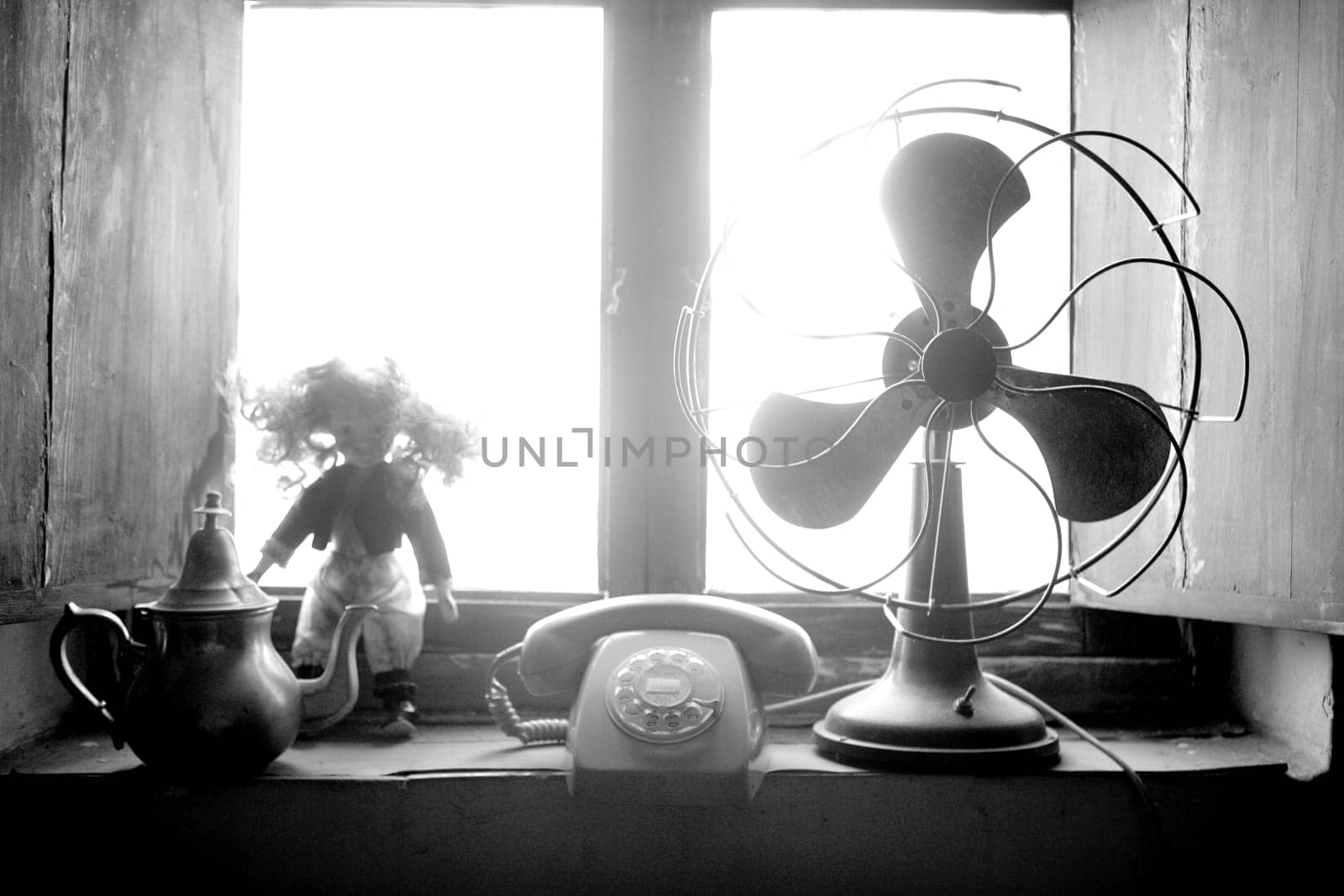 Antique vintage air fan, doll and phone at the window backlight