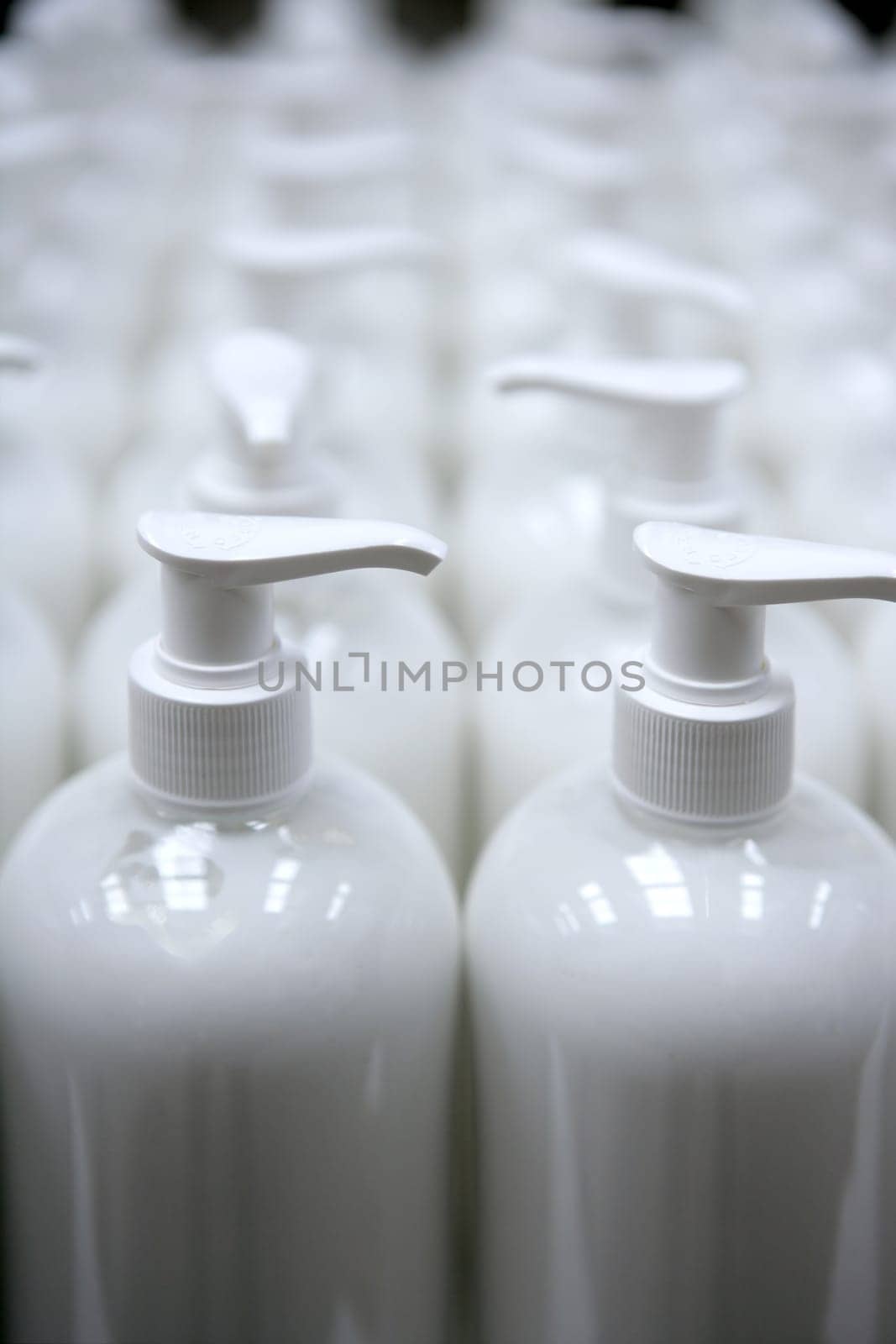 White plastic soap bottles in rows, cosmetics laboratory assembly line