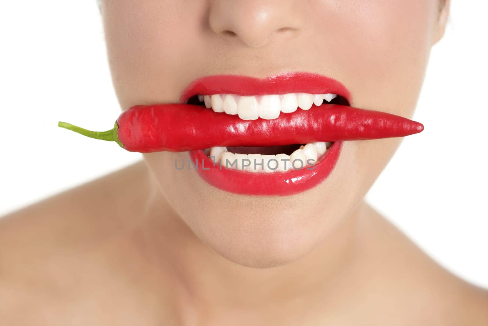 Beautiful woman teeth eating red hot chili pepper