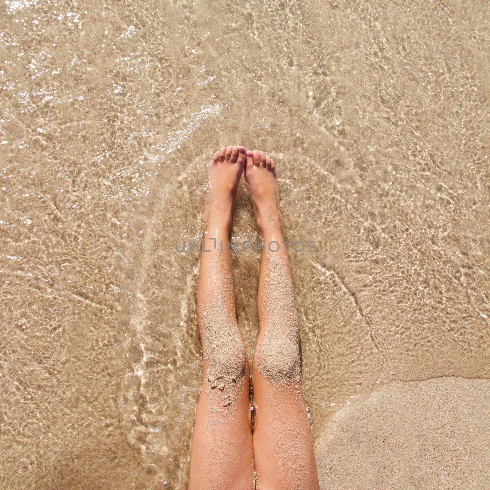 Children girl legs in beach sand shore at summer vacation