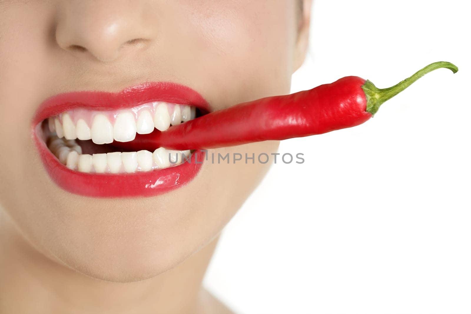 Beautiful woman teeth eating red hot chili pepper