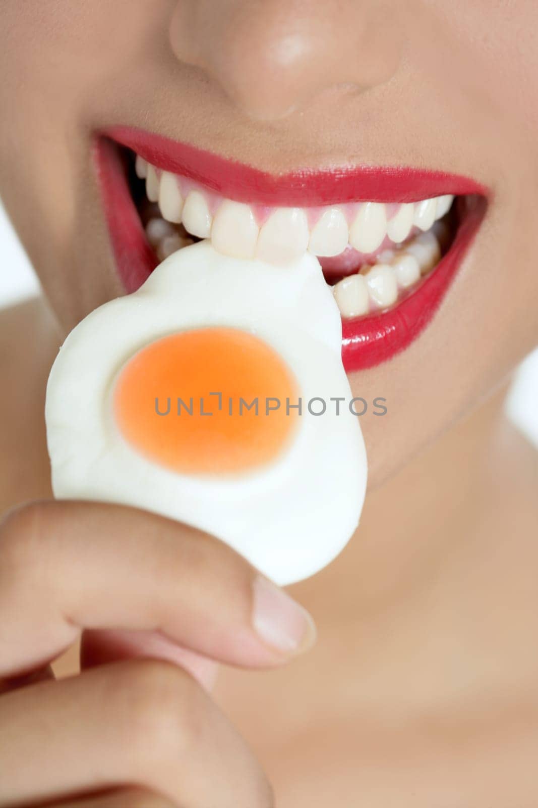 Beautiful woman mouth with red lips eating a jelly egg