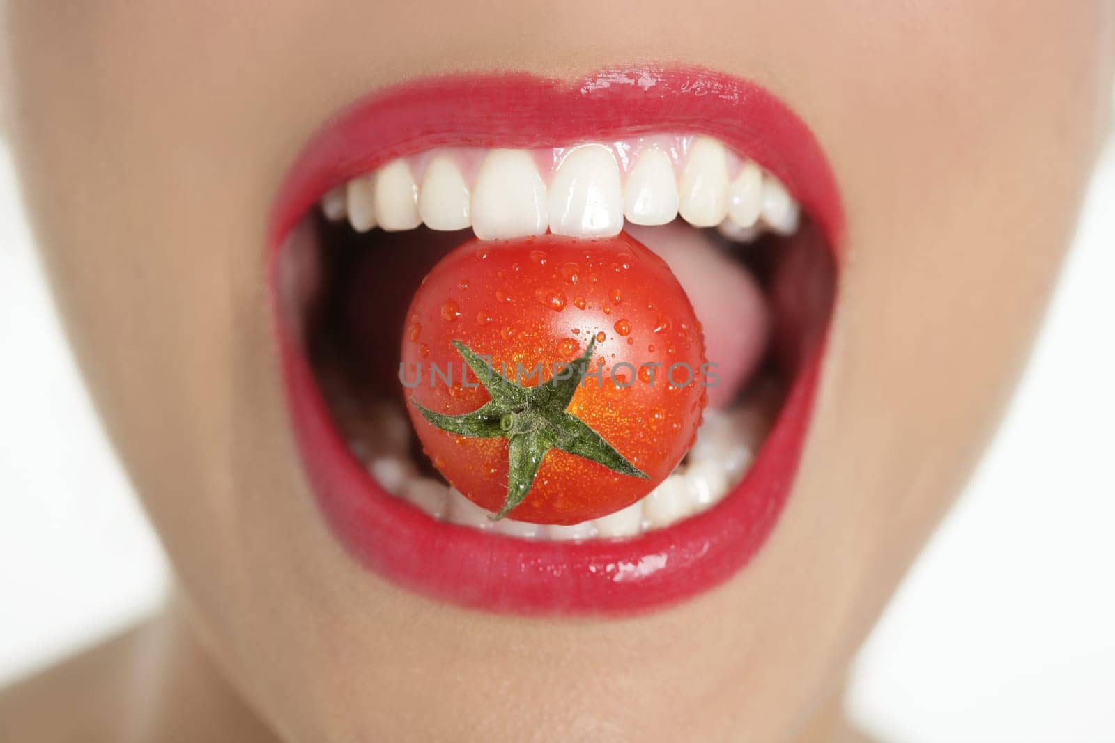 Eating a red tomato macro of woman teeth and red lips mouth