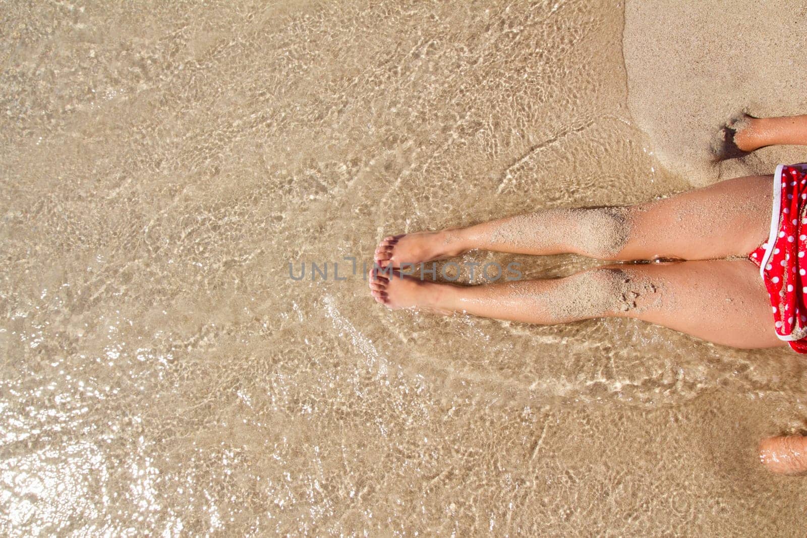 Children girl legs in beach sand shore at summer vacation