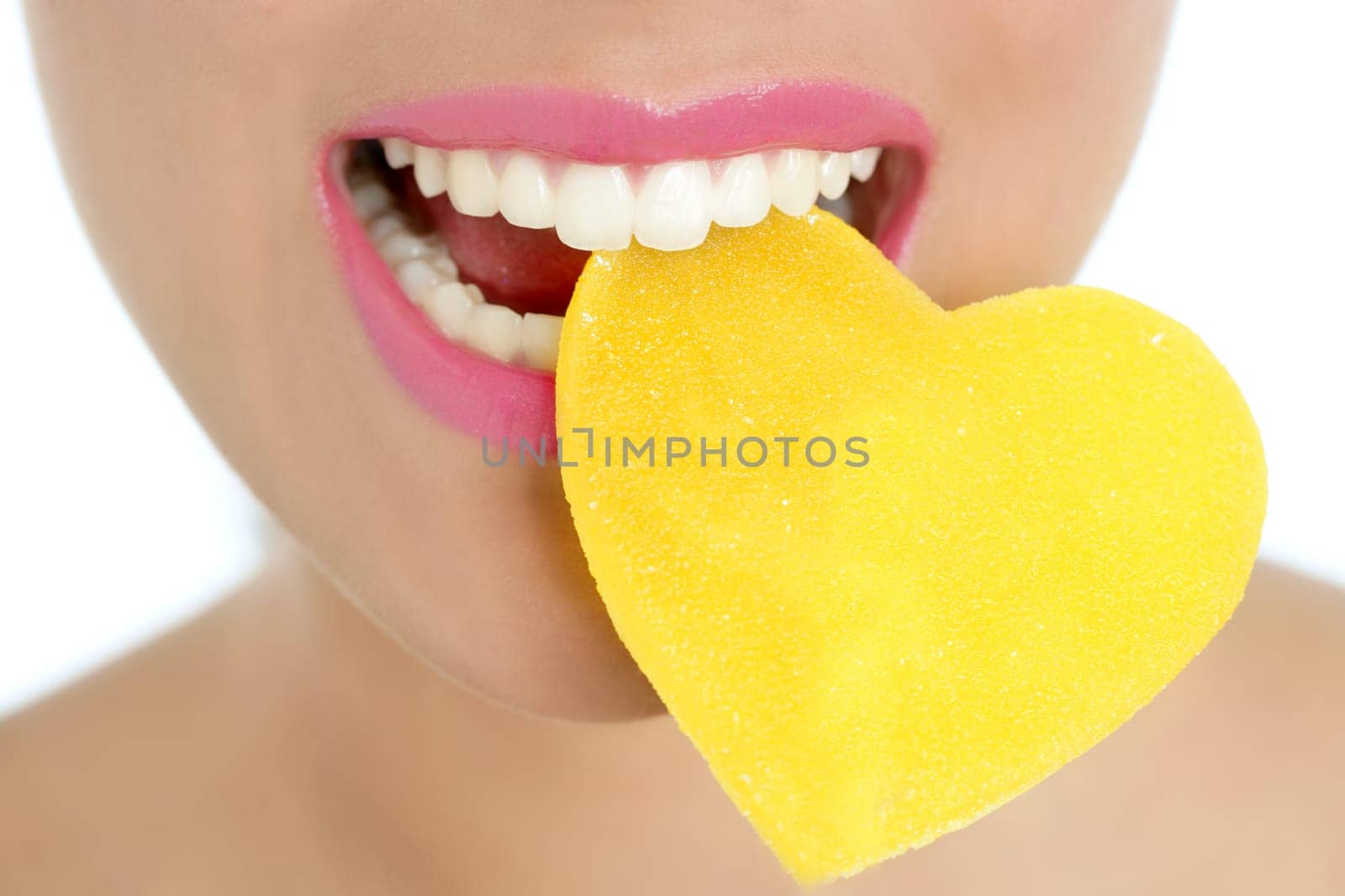 Heart shape candy on beautiful woman macro mouth
