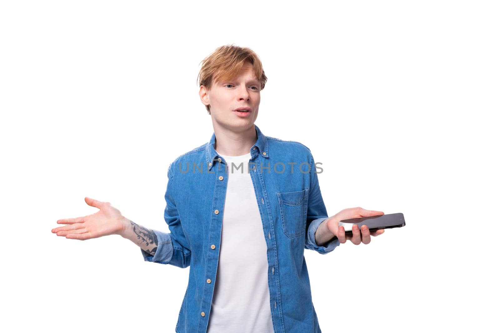 young guy with red hair in a denim shirt throws up his hands.