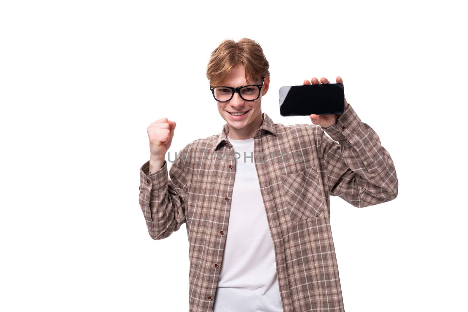 portrait of a young european red-haired guy in glasses with a smartphone in his hands.