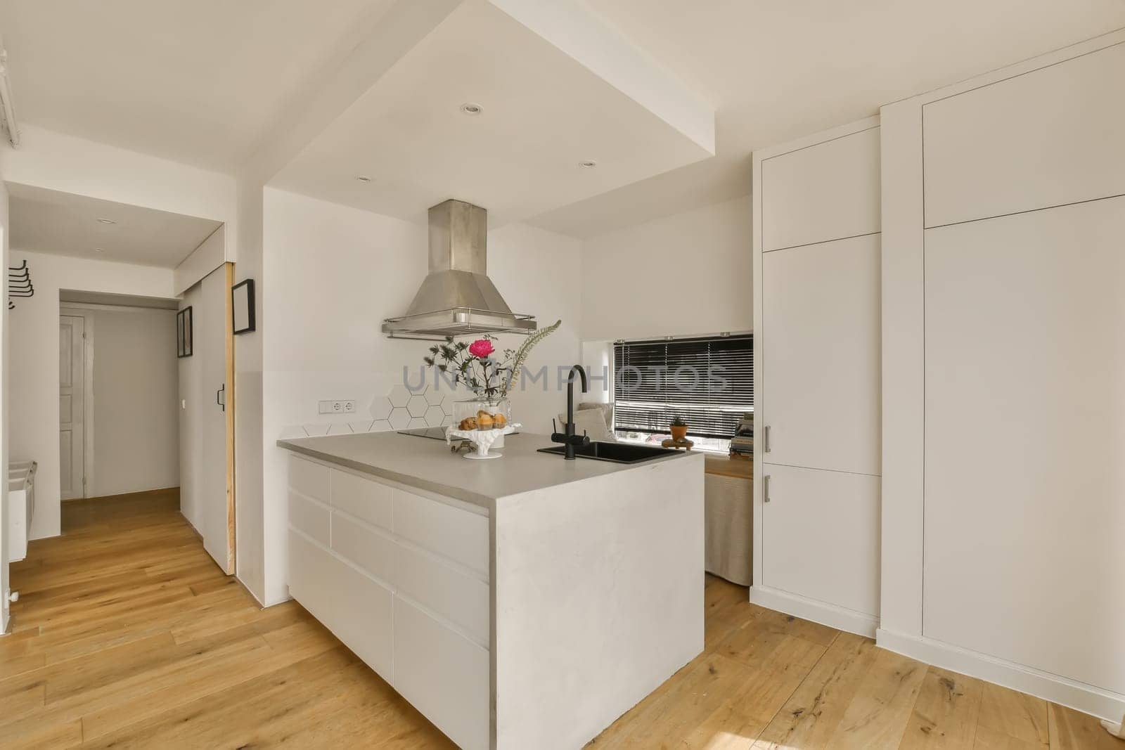 a kitchen with white cabinets and wood flooring in an open plan living room at the property is for sale