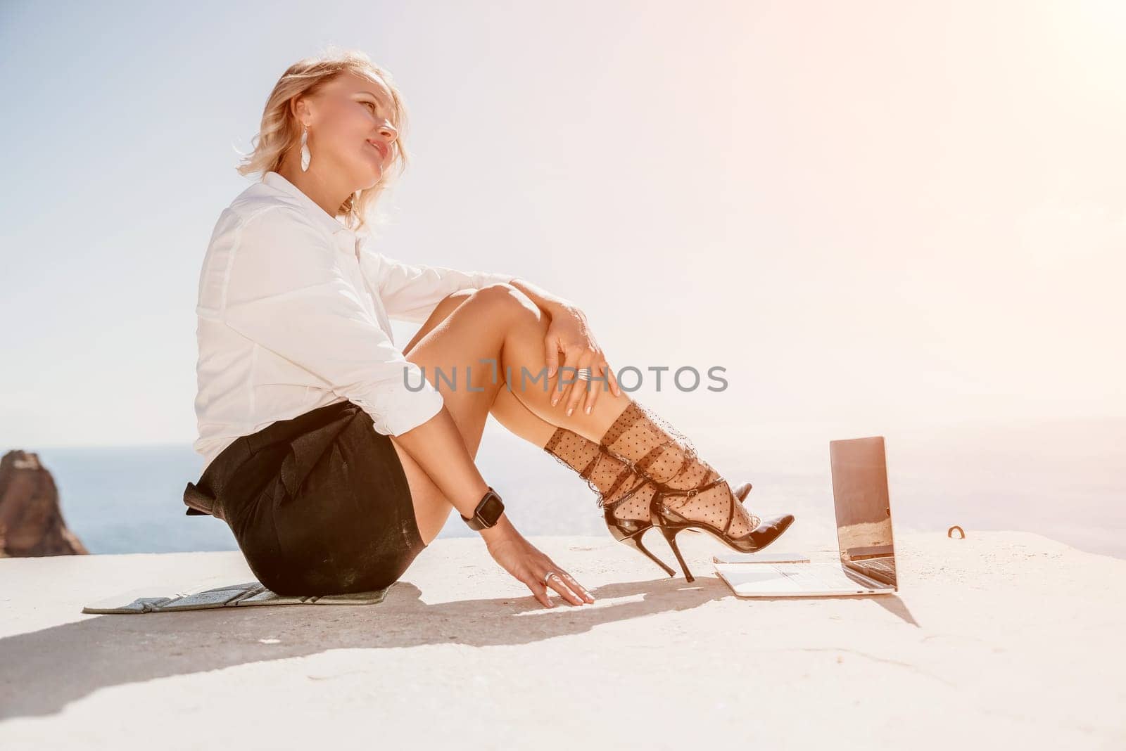 Woman sea laptop. Business woman in yellow hat freelancer with laptop working over blue sea beach. Girl relieves stress from work. Freelance, digital nomad, travel and holidays concept by panophotograph