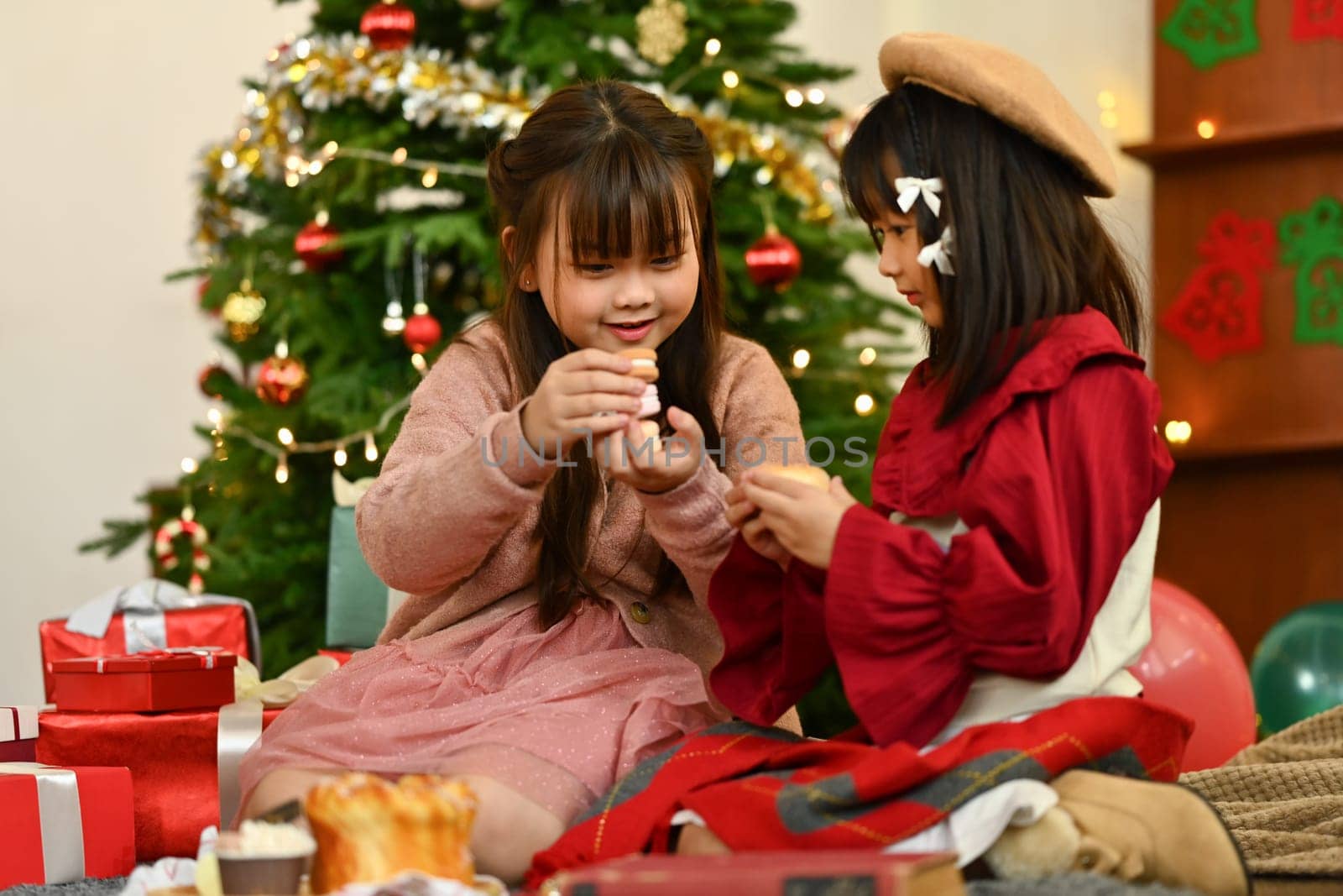 Cute little girls enjoying the warm Christmas atmosphere in cozy living room.