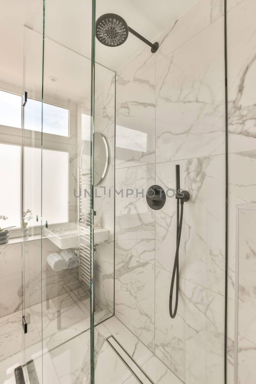 a bathroom with white marble walls and flooring, including a glass shower door that is open to the bathtub