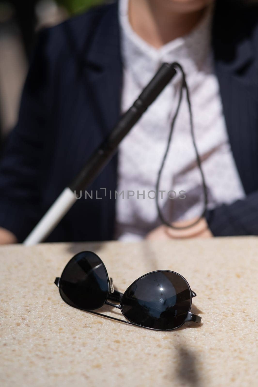 A blind woman in a business suit is sitting in an outdoor cafe. by mrwed54