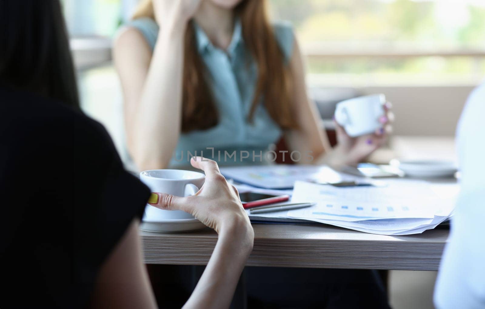 business people in cafe coffee break at table hold cup of coffee in arms closeup