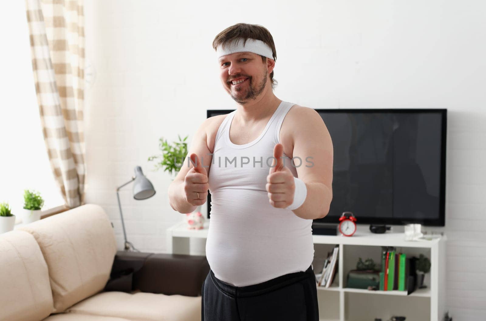 Young attractive man engaged in fitness at home holding dumbbell in hand trying to fight excess weight and loss