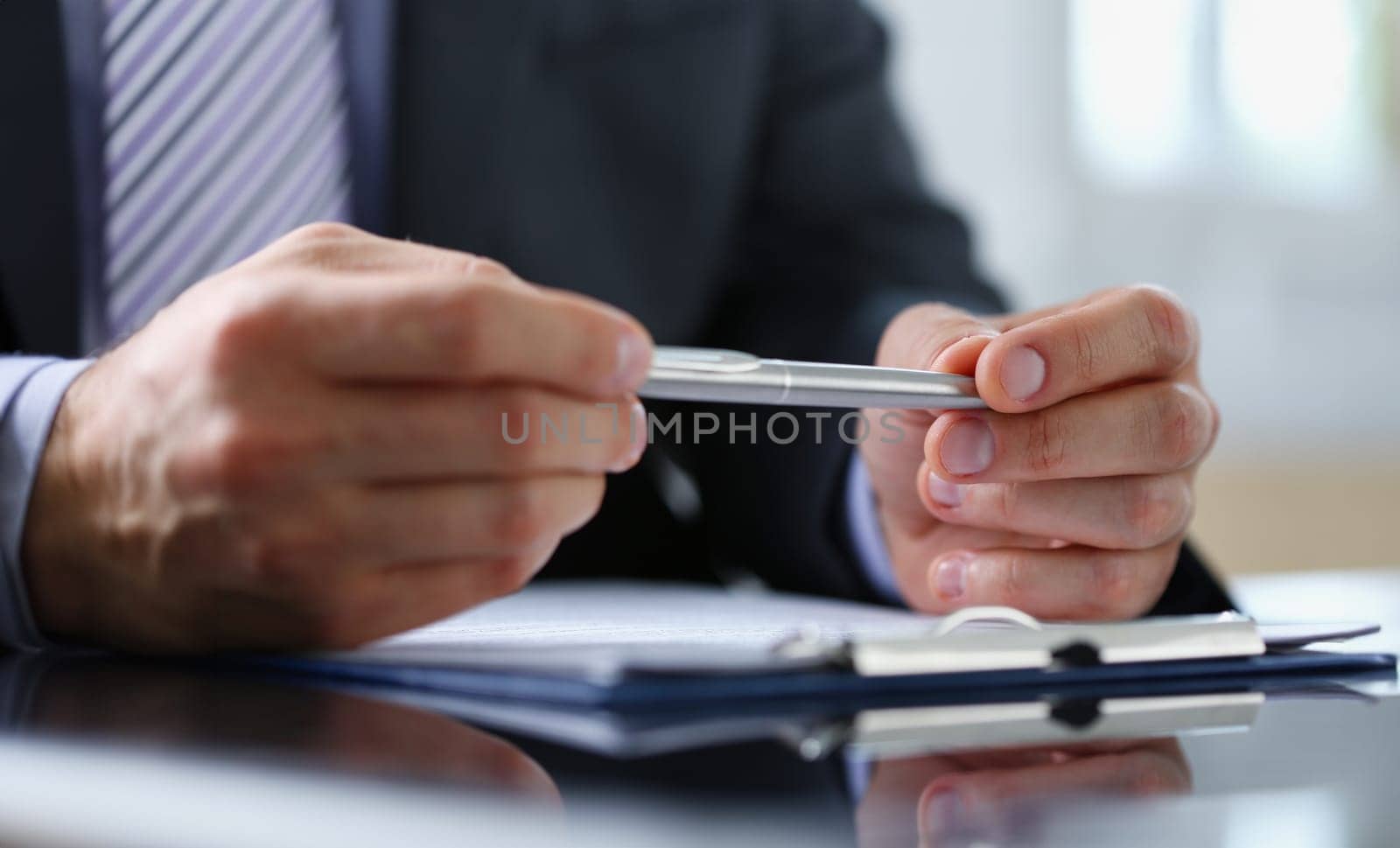 Male arm in suit and tie fill form clipped to pad with silver pen closeup. Sign gesture read pact sale agent bank job make note loan credit mortgage investment finance chief legal law concept