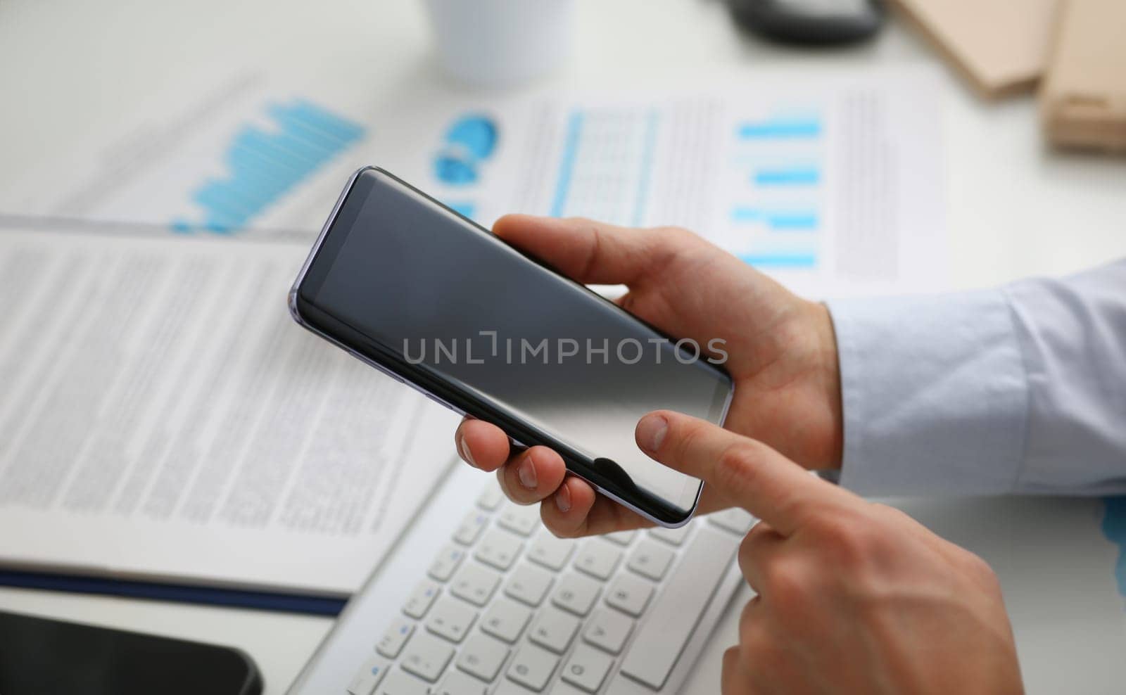 A businessman holds a new smartphone in his hand The mobile application market shows a display. You can insert your image for advertising or financial statistics.
