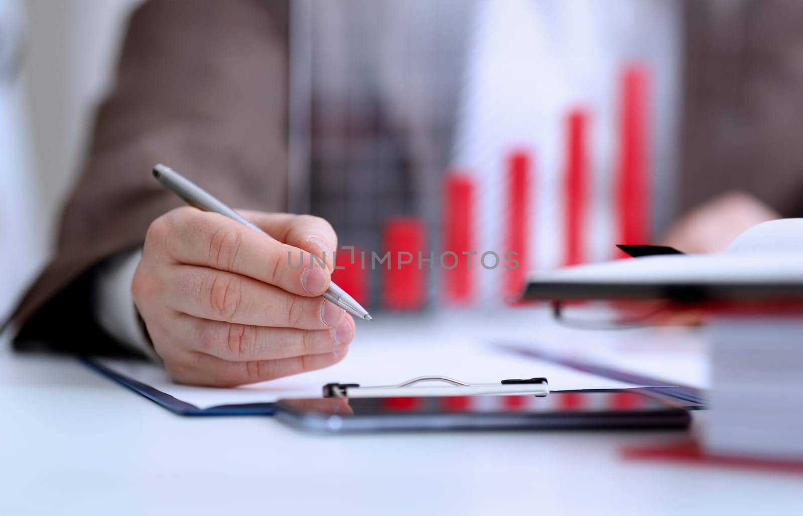 Male arm in suit and tie hold silver pen filling schedule in notepad at office workplace closeup. Legal law consult assistance gesture or finance investment advisor clerk job information gesture