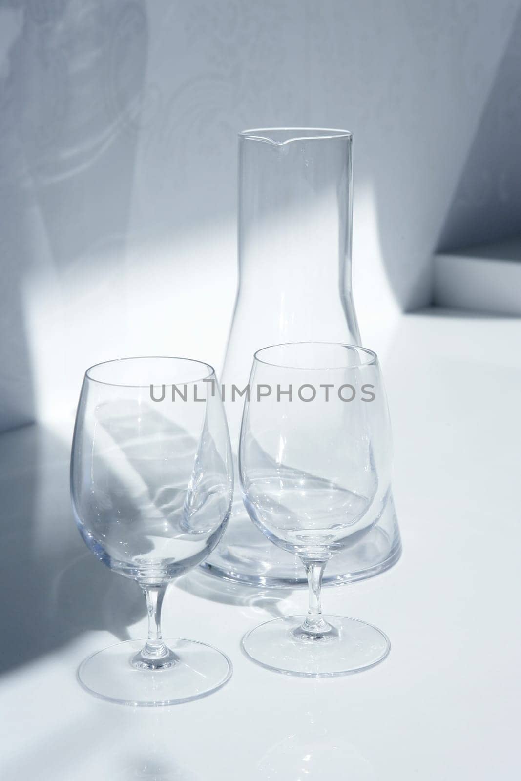 Water glass and bottle with transparent shadows in white kitchen