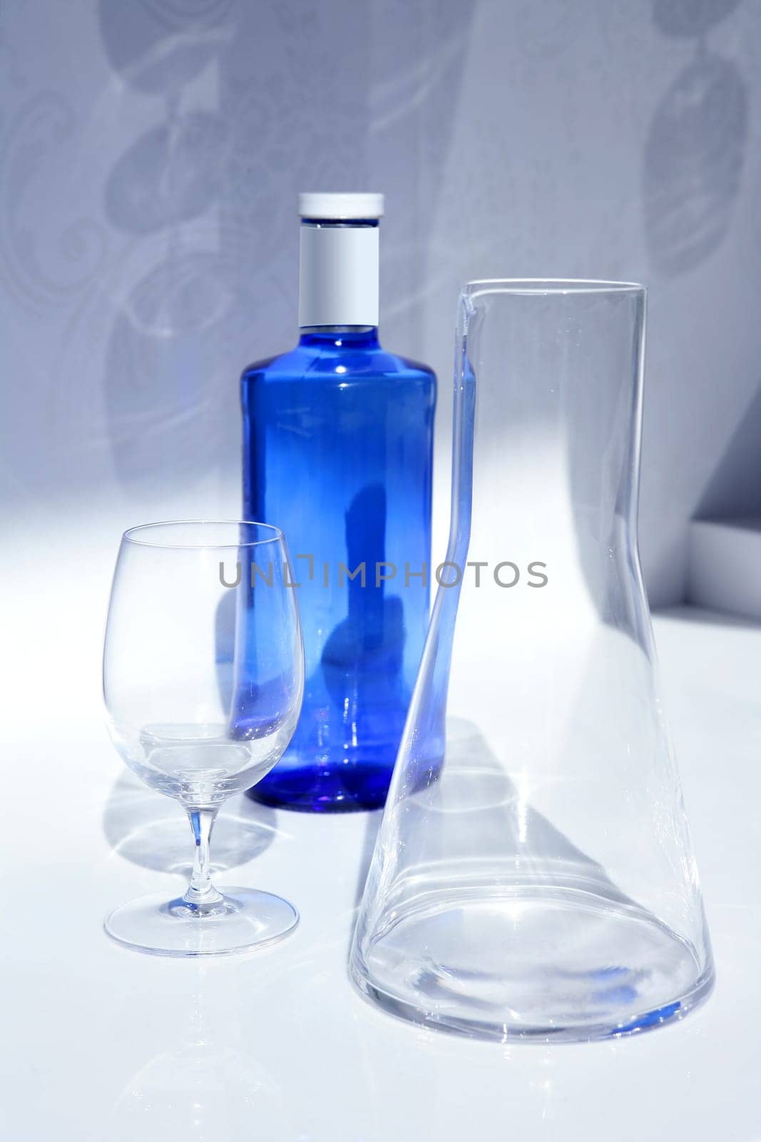 Blue water bottle with glass, transparent shadow in white kitchen