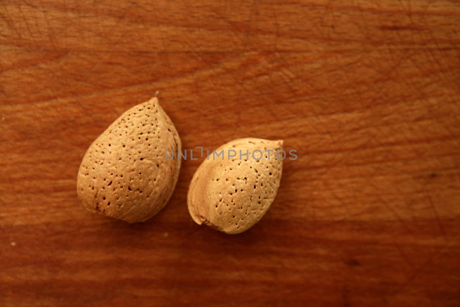Two almond nuts on a golden wood aged table
