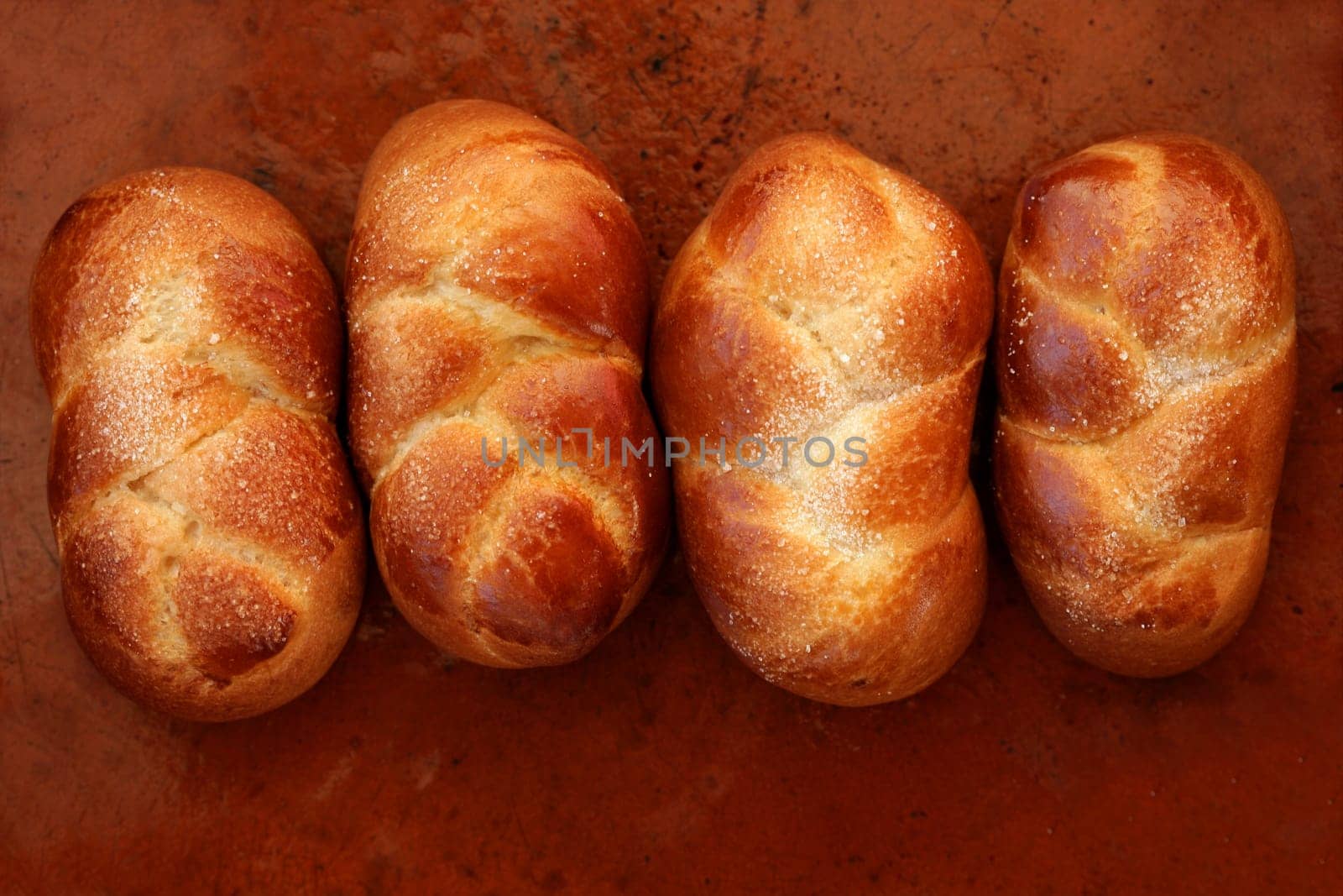 Four brioche pastries in a row, orange brown clay background, bakery