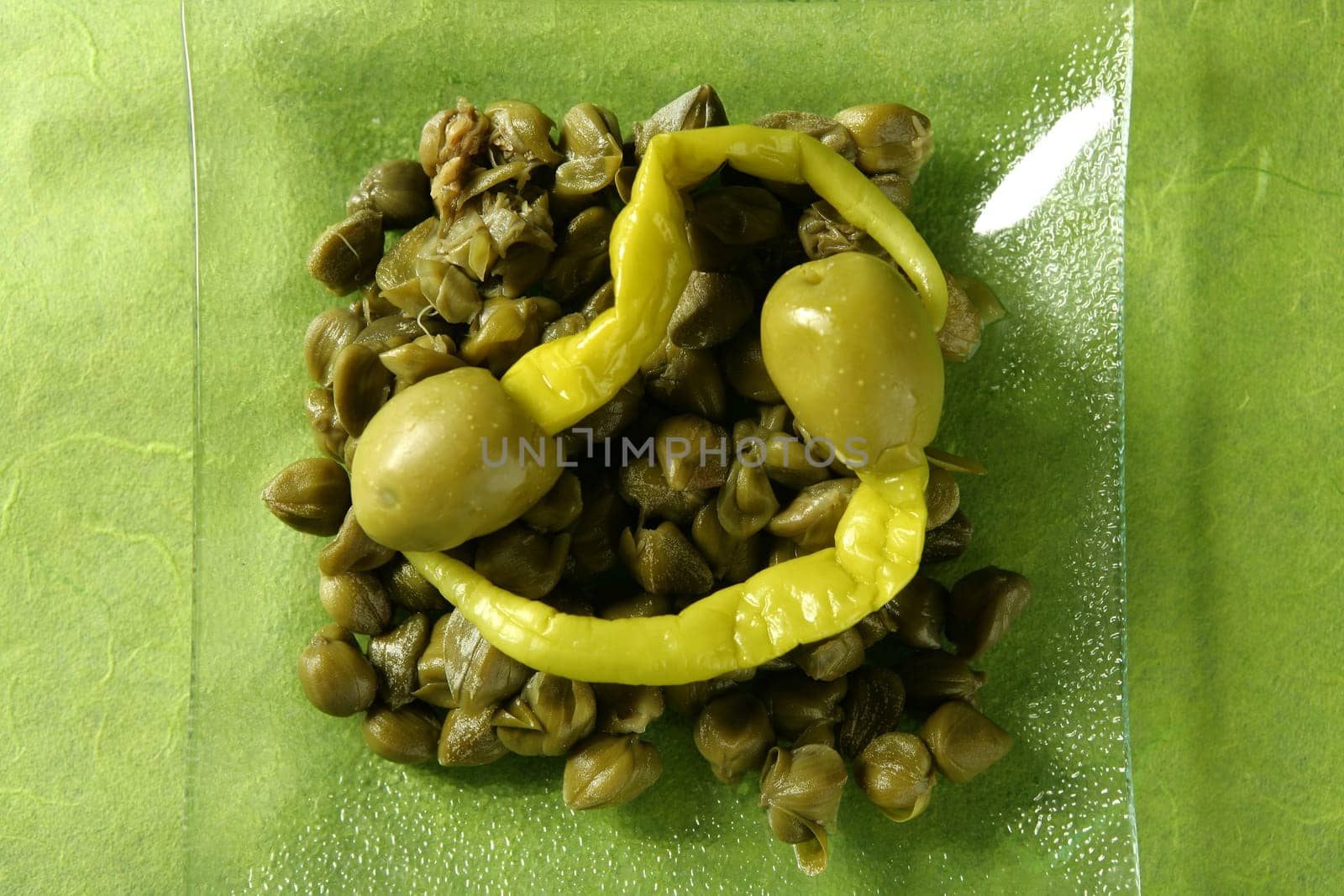 Capers, olives and hot pepper snack , green background