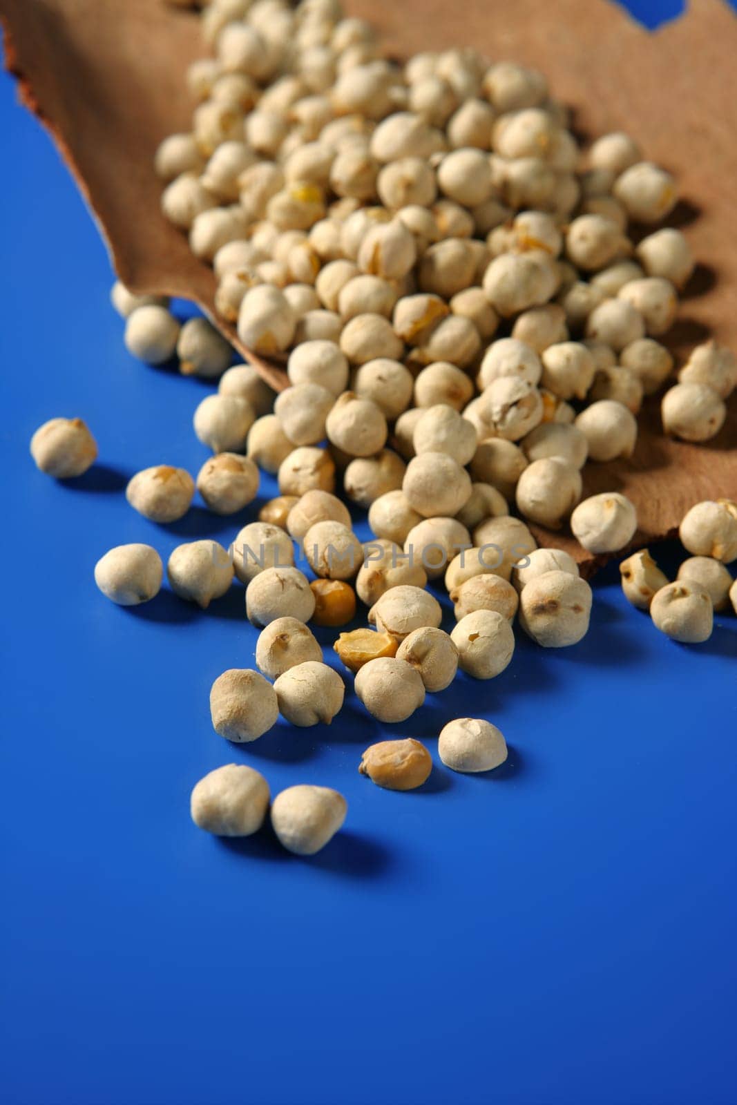 Chickpeas still spread over vivid blue background