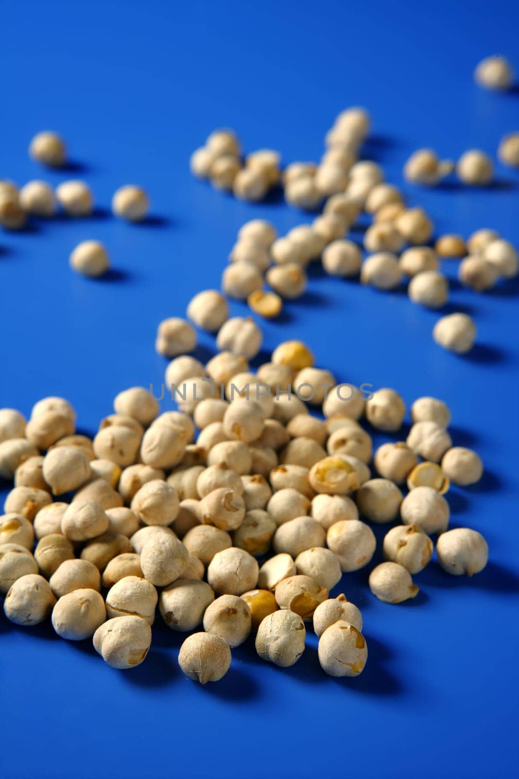 Chickpeas still spread over vivid blue background