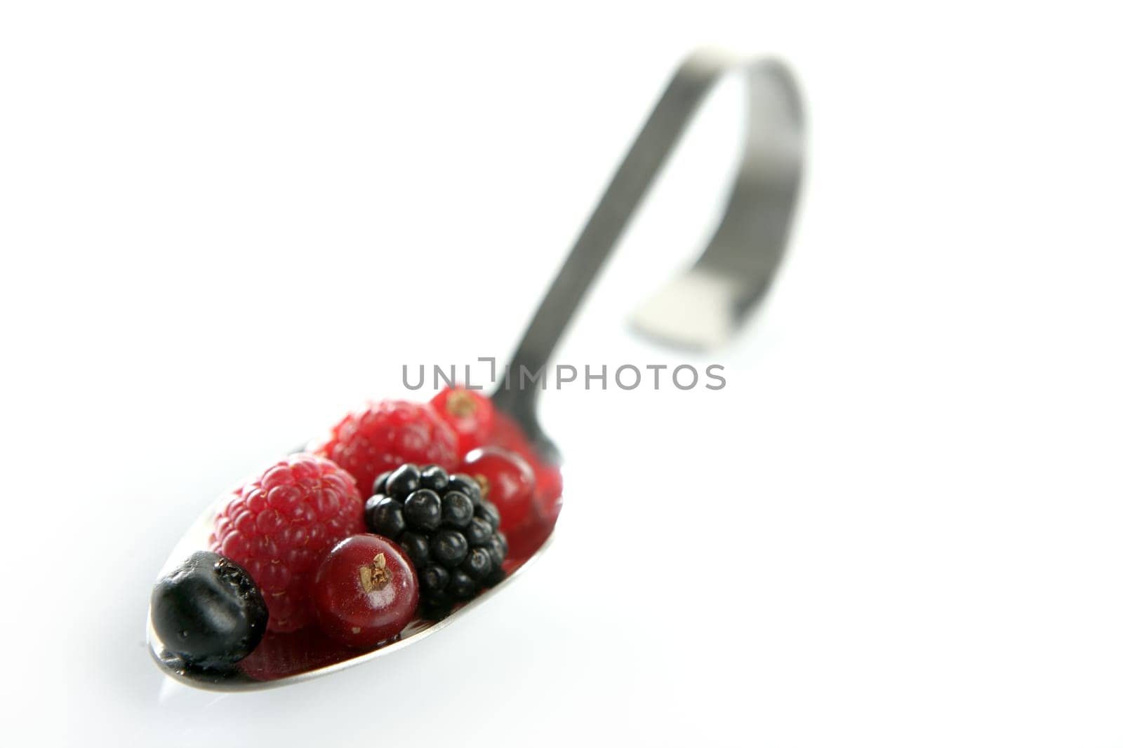 Varied berries in a curved spoon in white background