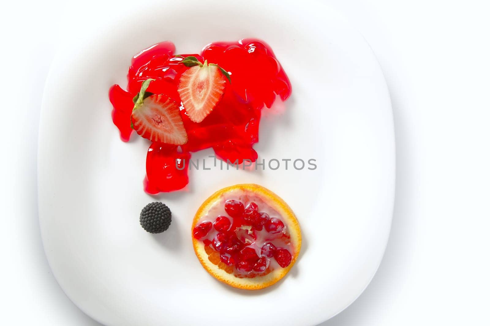 Modern dessert plate with strawberries, berries, jelly and orange