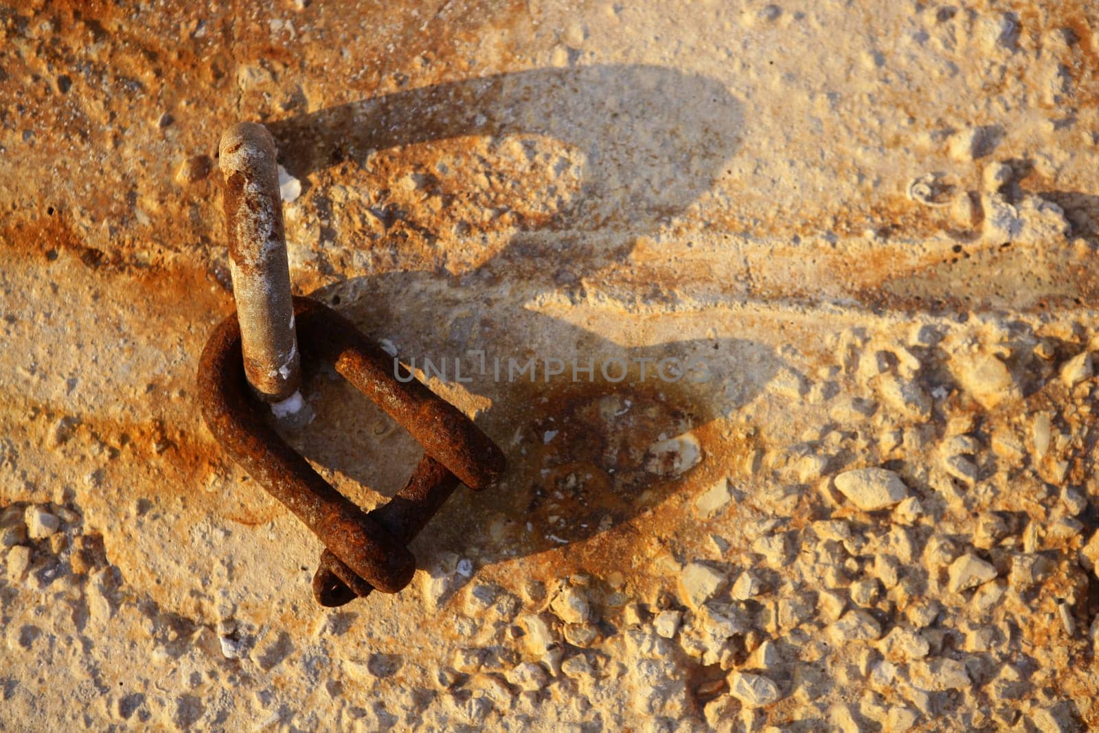old rusted shackle on the harbor concrete stones, golden sunset light