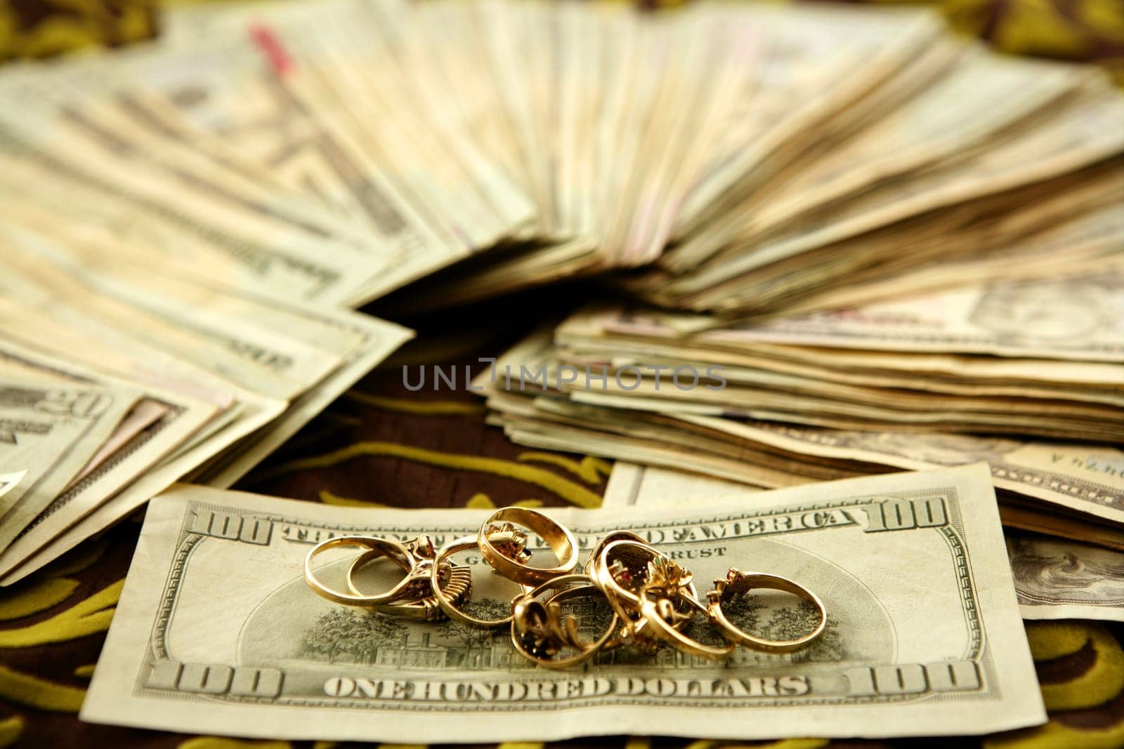 Dollar notes and gold rings over tablecloth, studio recreation