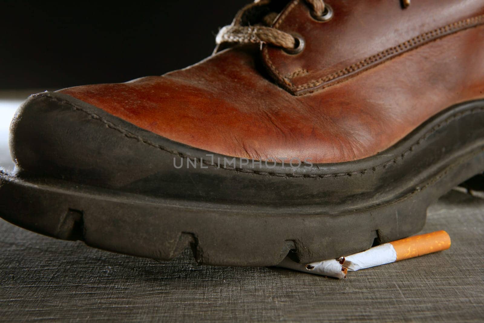 broken cigarette tread by a boot, tobacco addiction metaphor