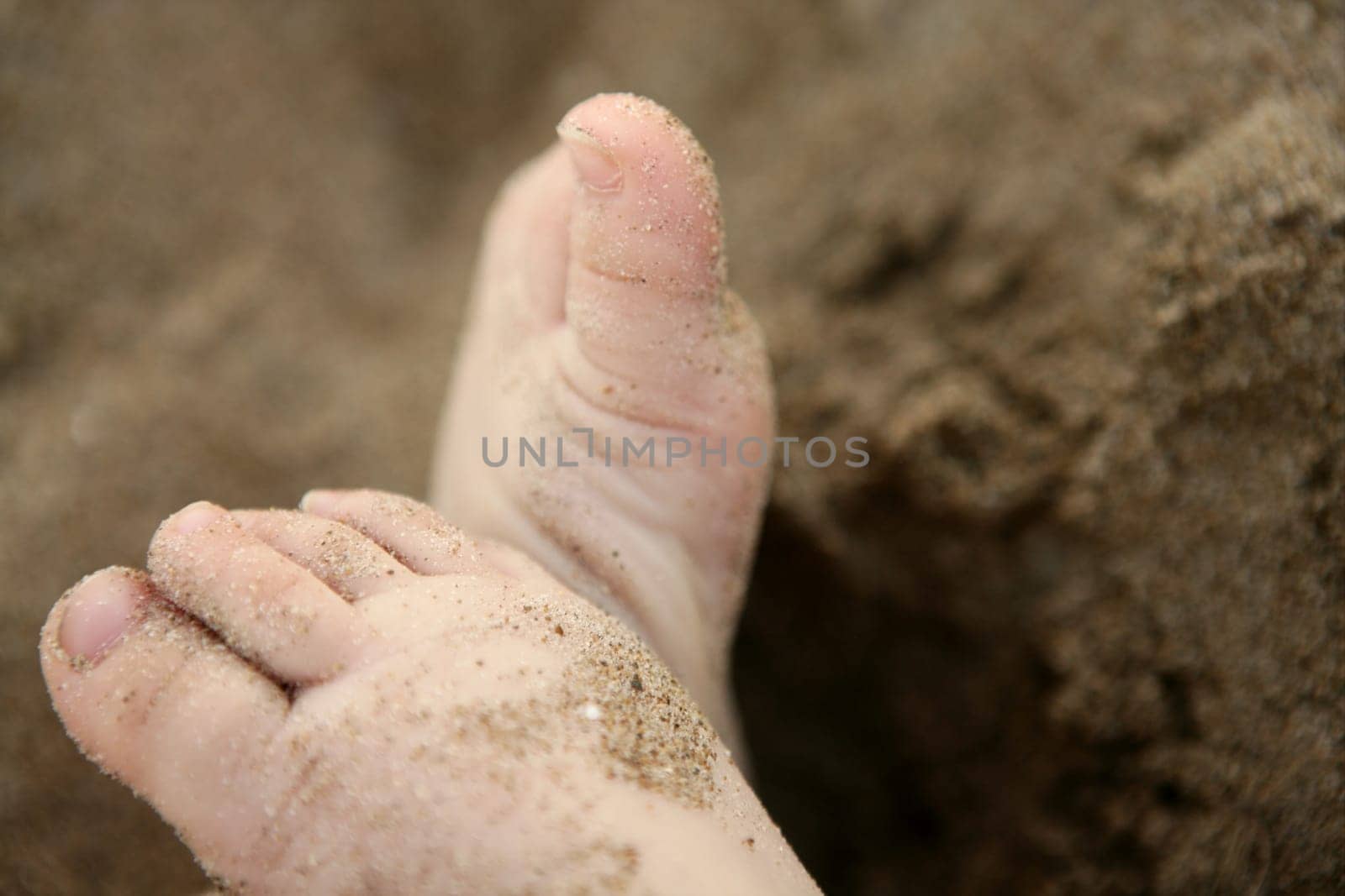 Baby feet over the golden brown beach sand