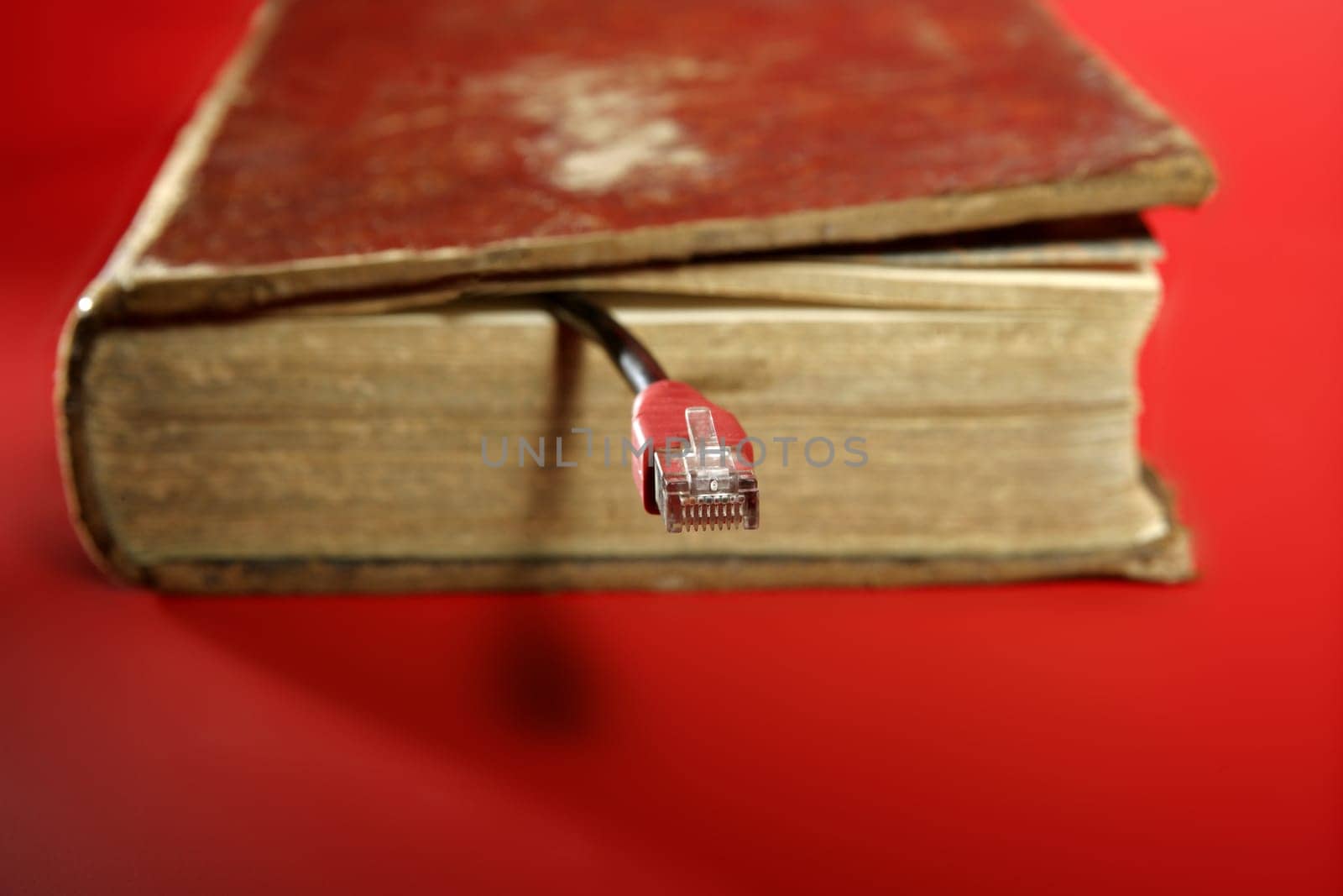 Network RJ45 cable connection coming from old book over red background