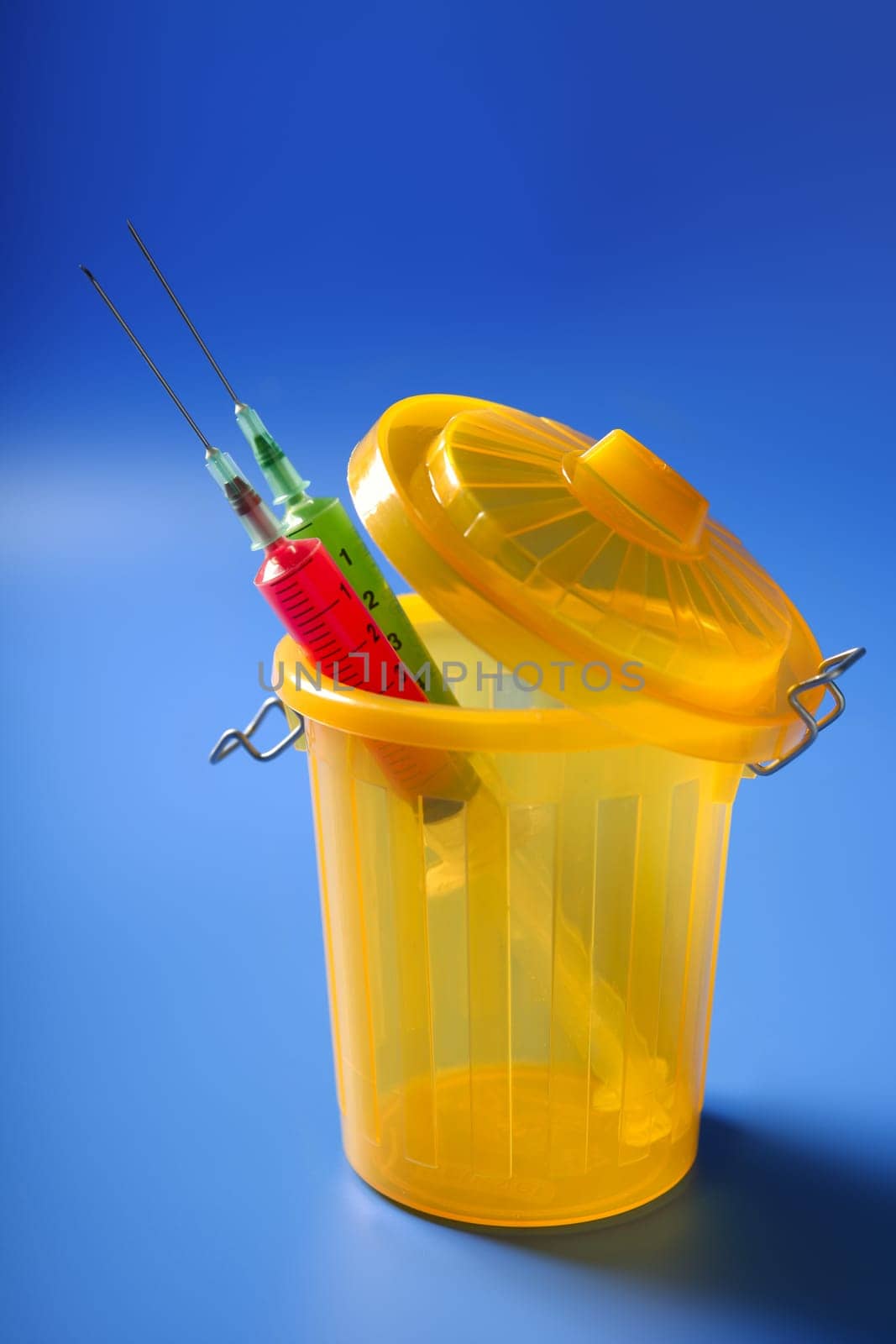 Two red and green syringe on the trash, addiction metaphor
