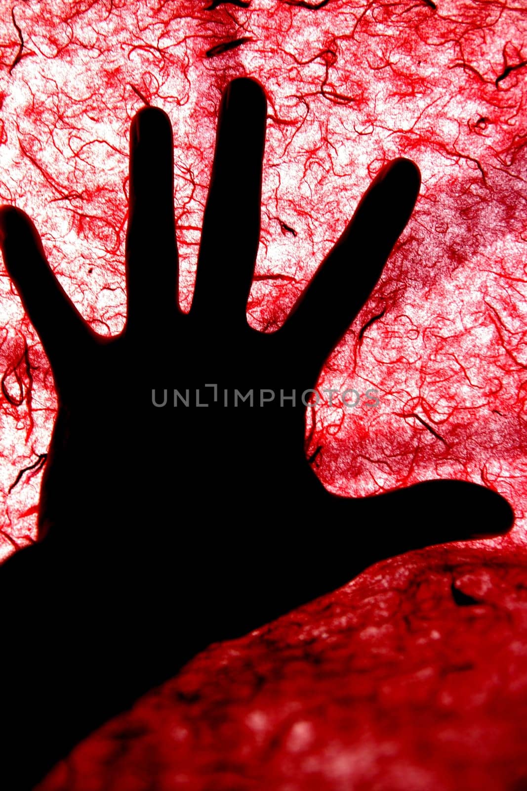 Backlight of human hand over red textured surface, bloody