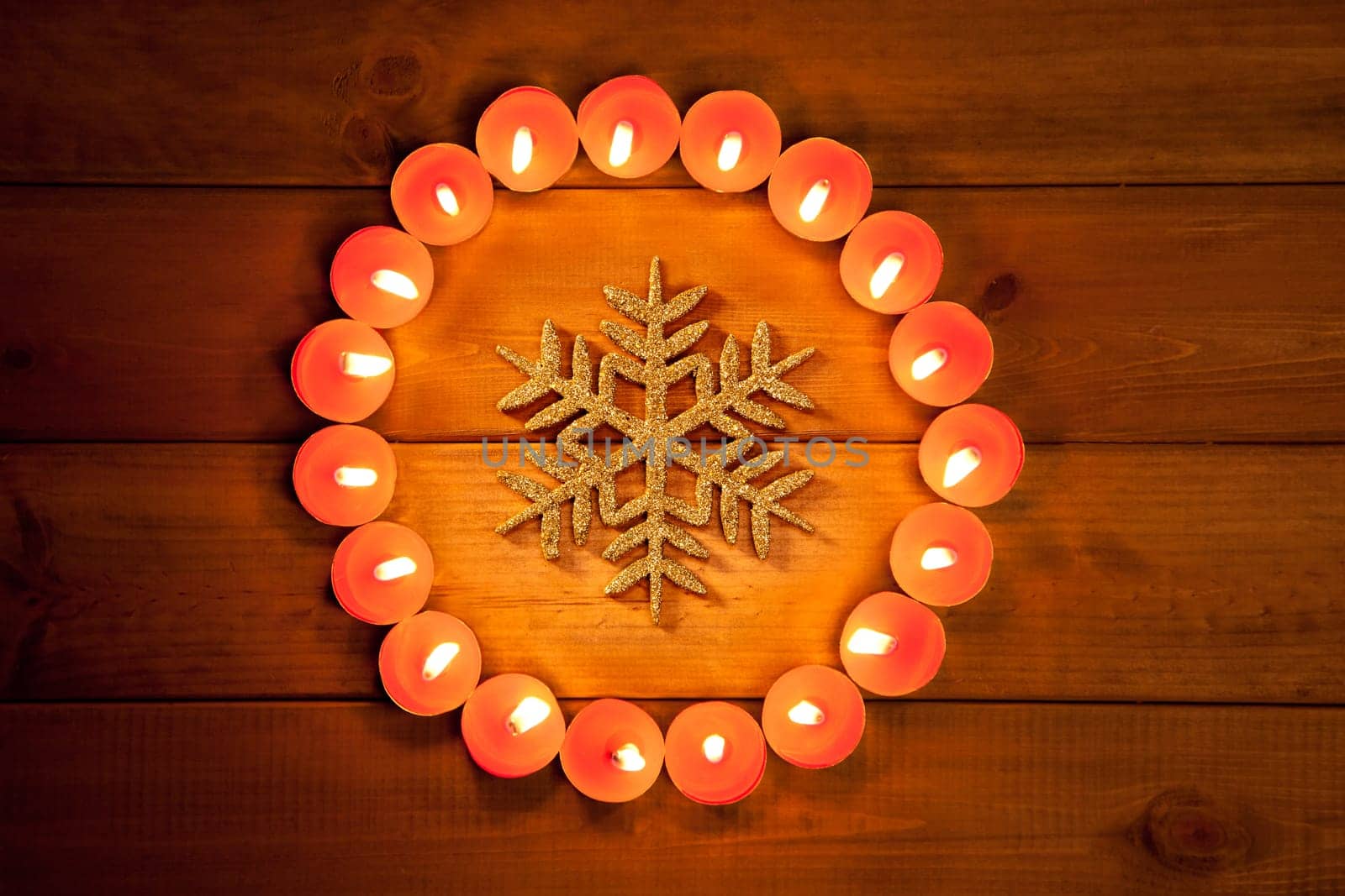christmas candles circle over wood and golden snowflake symbol