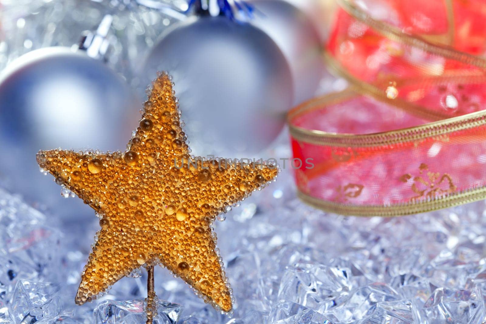 christmas golden star symbol with silver baubles and red ribbon on ice