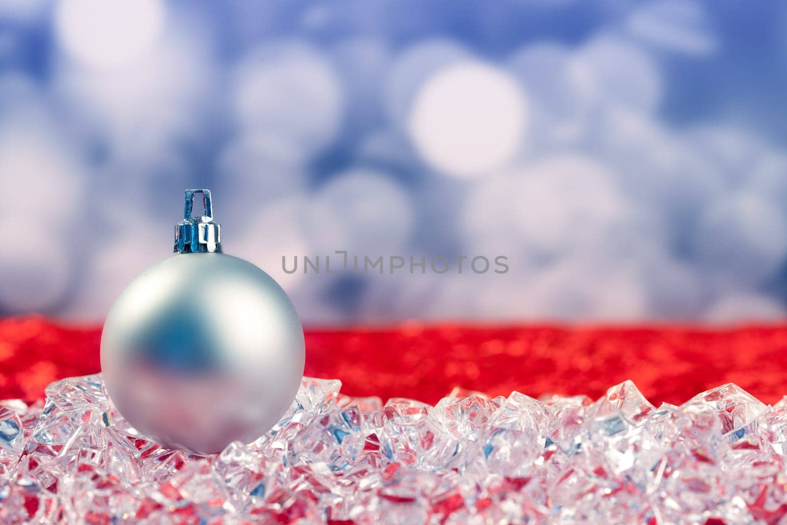 Christmas silver bauble on ice cubes with blue lights bokeh background