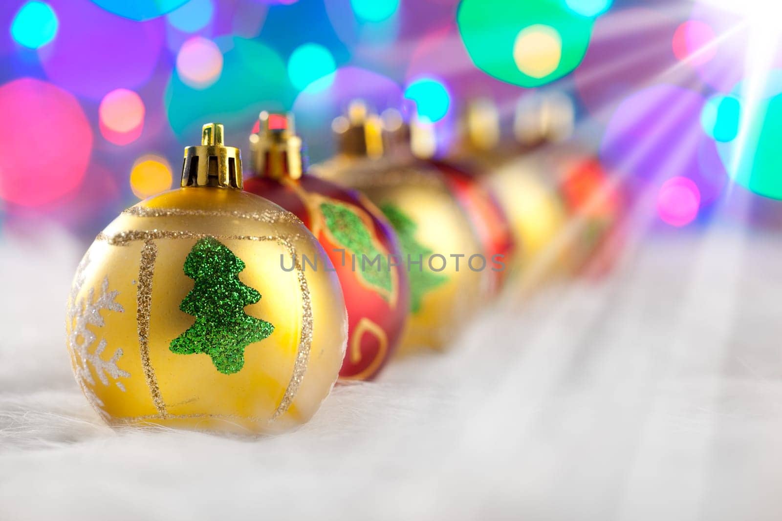 christmas golden red baubles in a row with colorful lights background