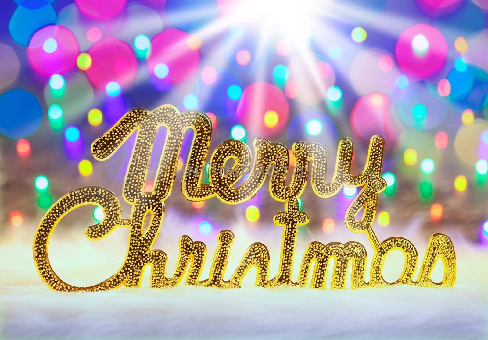 Merry christmas written in gold with colorful glowing lights