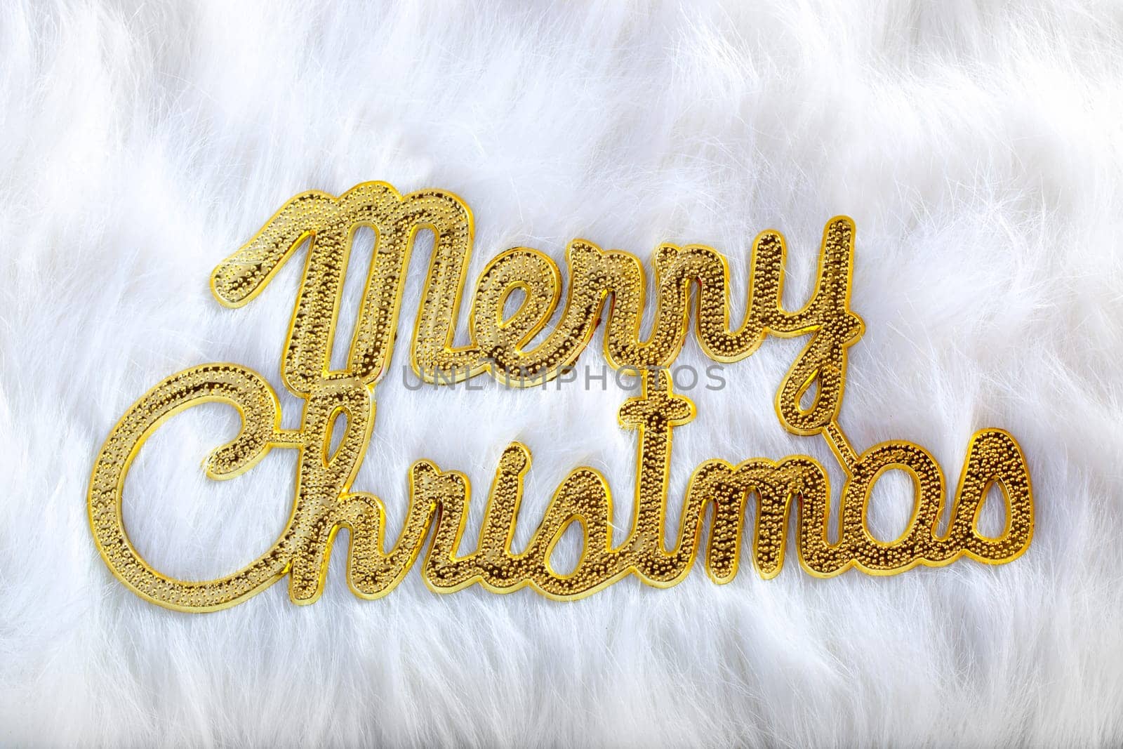 Merry christmas written in gold on white fur in winter holidays