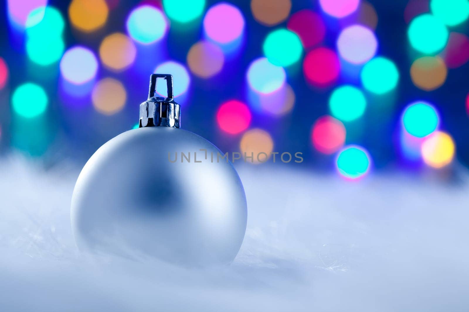 Christmas silver bauble in colorful blurred lights background