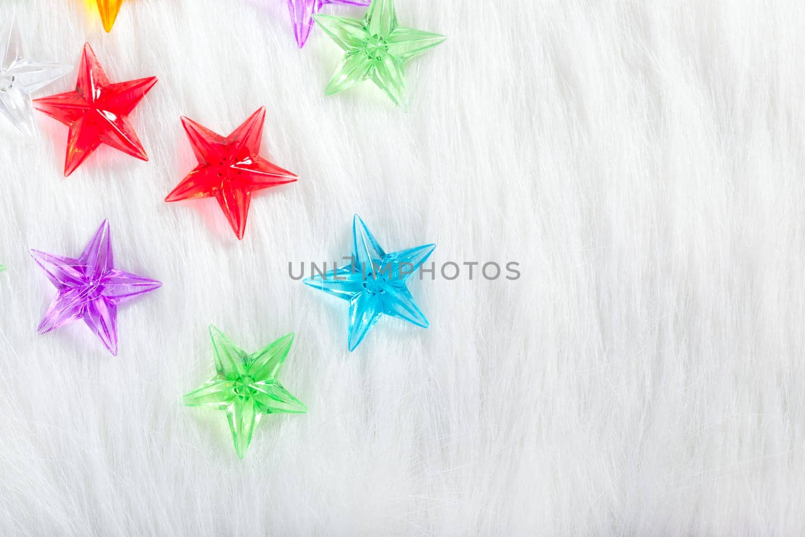 christmas colorful glass stars over white fur background as snow
